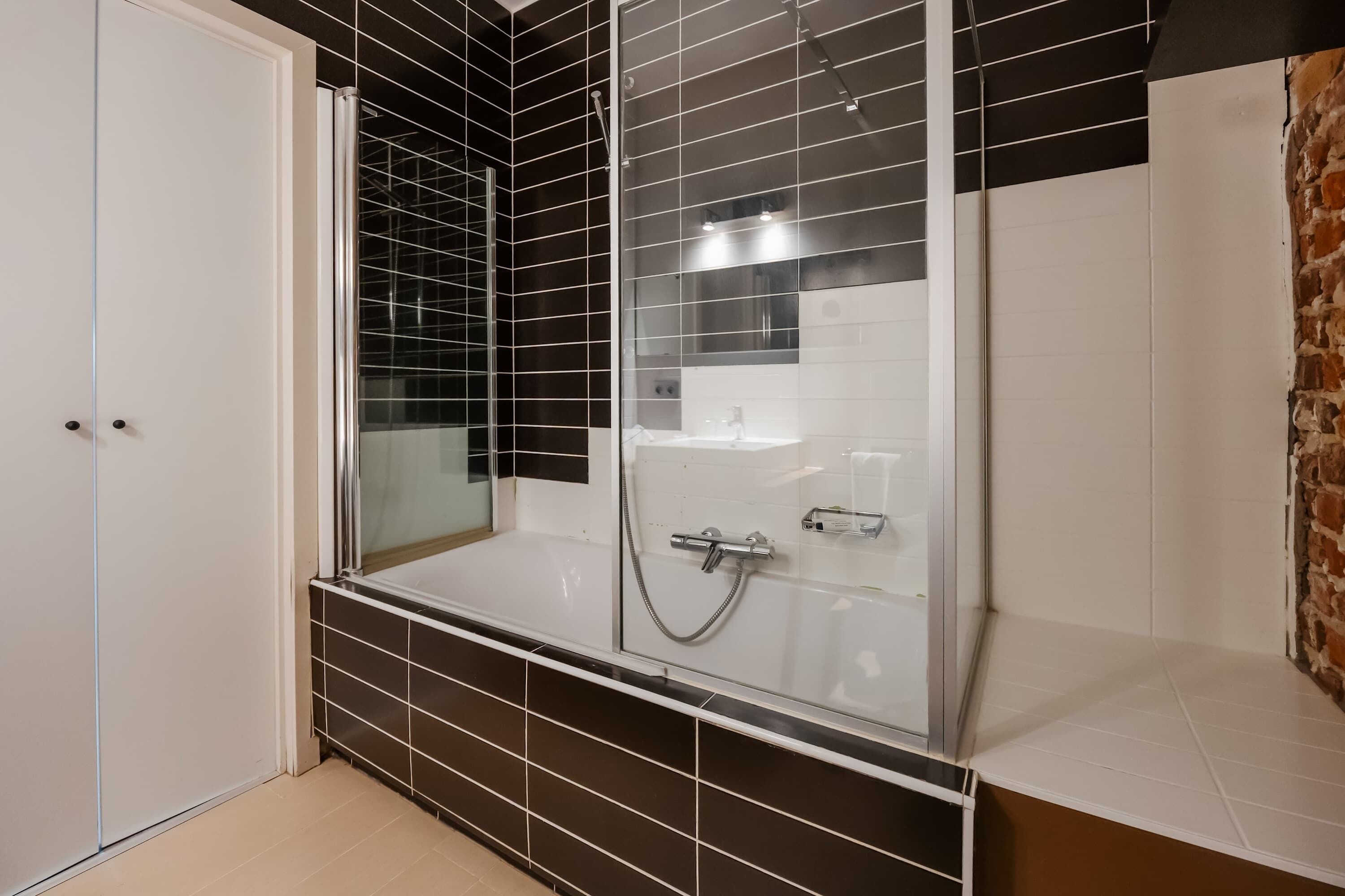 A bathroom with a glass-enclosed shower, a white sink, and a tiled floor.