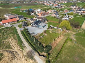 Vista aérea de una zona residencial con casas, un edificio grande con garaje y campos circundantes.