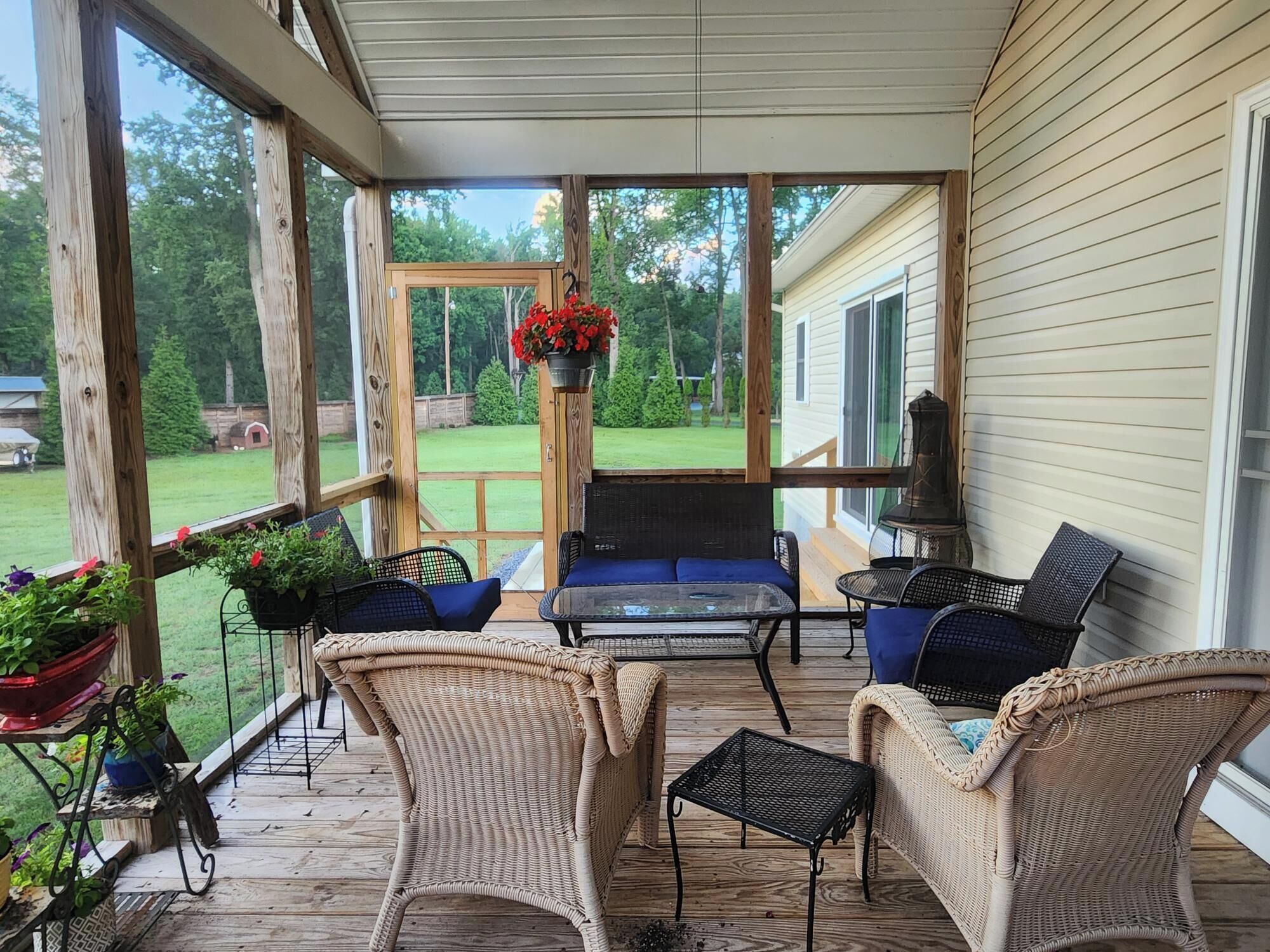 A covered porch with wicker furniture, a table, and potted plants.