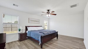 Un dormitorio con cama de madera, ventilador de techo y ventana con persianas.
