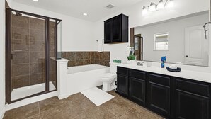 Un baño moderno con ducha a ras de suelo, bañera y retrete.