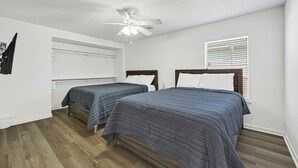 Un dormitorio con dos camas, un ventilador de techo y una ventana con persianas.