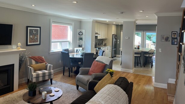 Ein geräumiges Wohnzimmer mit Kamin, Essbereich und einer Küche im Hintergrund.