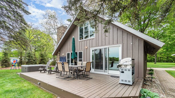 A modern house with a deck, outdoor seating, and a grill. - Stunning Lakefront Cottage with Beach & Hot Tub (Alger)
