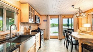 Cocina moderna con armarios de madera, encimera negra y vistas a un lago a través de un ventanal.
