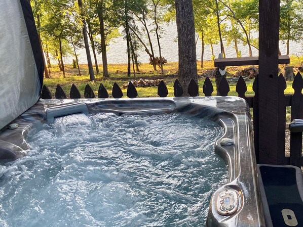 A hot tub with a wooden deck and a view of a lake.