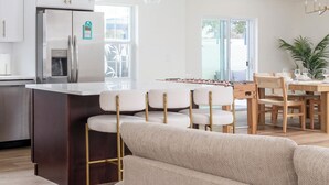 Una cocina moderna con una isla central, taburetes de bar e iluminación colgante.