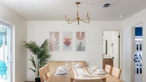 Un comedor con mesa de madera para cuatro, una planta en maceta y arte abstracto en la pared.