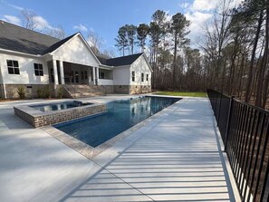 Ein Wohnhaus mit Swimmingpool, überdachter Terrasse und Holzterrasse.