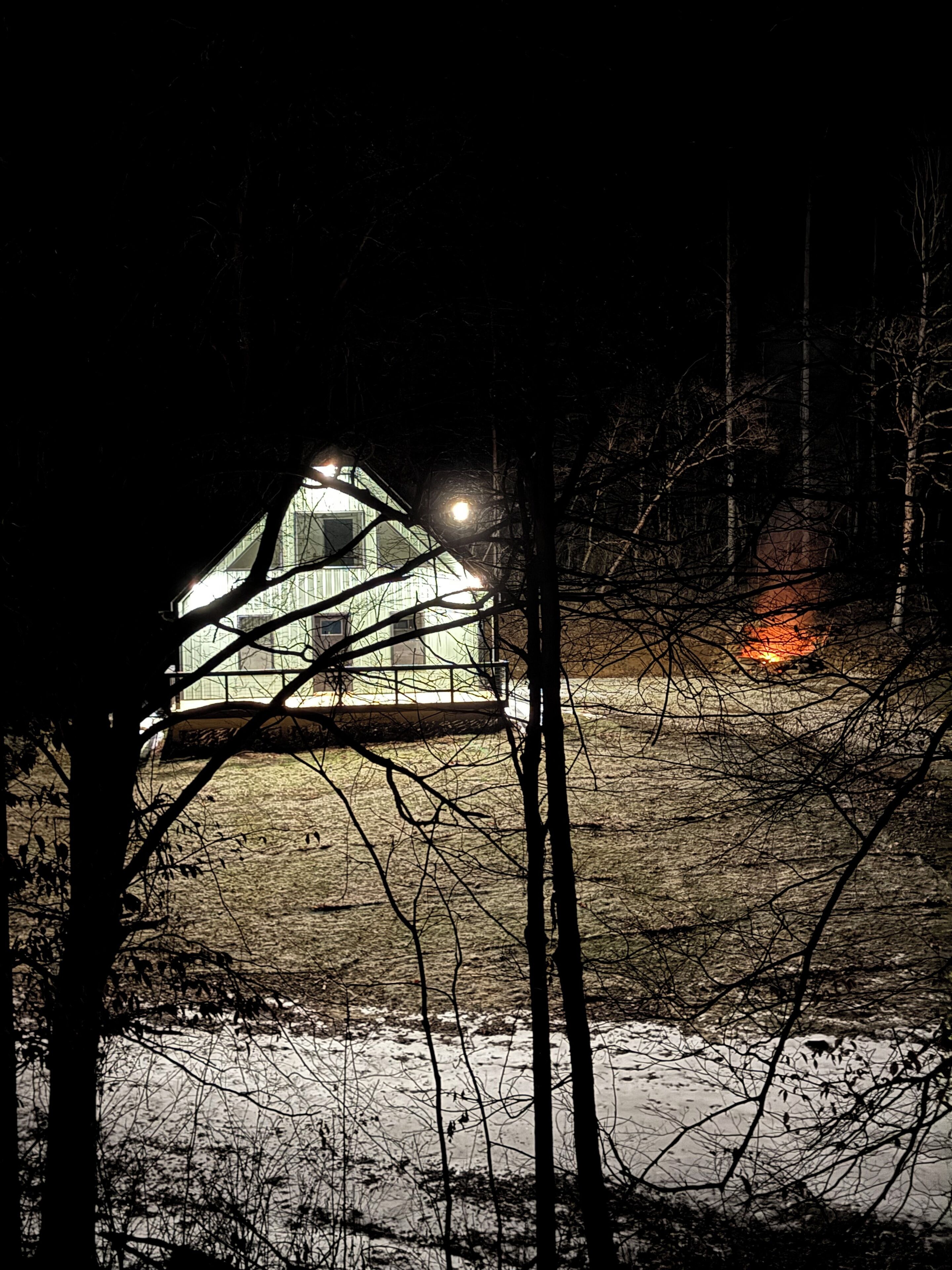 Una baita con un ingresso anteriore ben visibile e un portico, circondata da alberi e terreno innevato.