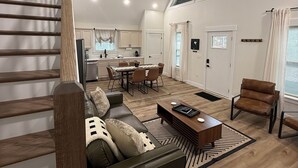 Ein geräumiger Wohnbereich mit Esstisch, Sofa und Treppe.