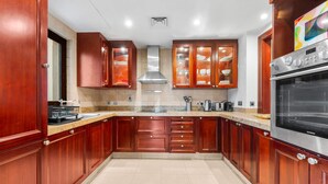 A kitchen with wooden cabinets, a stainless steel range hood, and a Siemens oven. - Stayshort - 2 Bedroom in Oldtown Sleeps 4 Close to Burj Khalifa (Dubai)