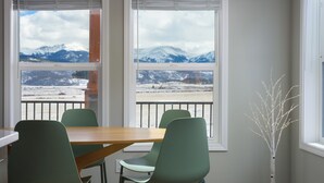 A dining area with a table and chairs, large windows with a mountain view, and a white tree sculpture. - Panoramic Views | 13 Min to Winter Park | Sleeps 8 (Tabernash)