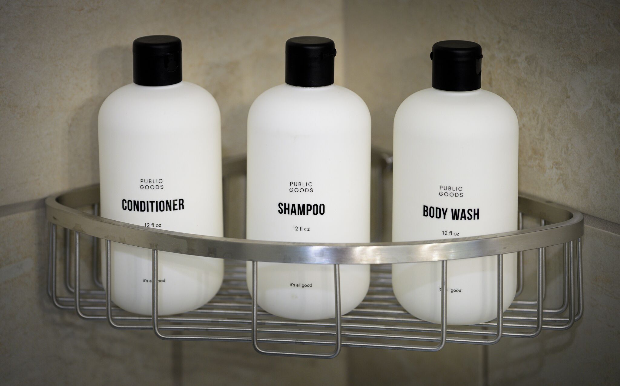 Trois flacons blancs de produits de toilette, disposés sur un plateau en métal.