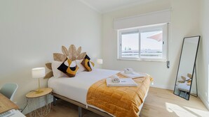 A hotel room with a bed, a round side table with a lamp, a mirror, and a view of the outside through a window. - Serra&Rio no Sado - By Y Concept (Setúbal)