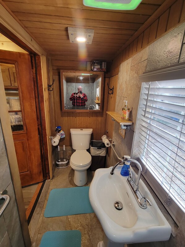 A compact bathroom with a toilet, sink, and mirror.