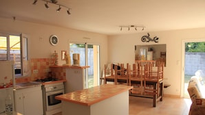 Une cuisine avec un îlot central, une table à manger avec des chaises, une cuisinière et un réfrigérateur.