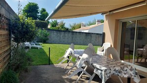 Une terrasse avec une table et des chaises, un espace abrité et une vue sur le jardin arrière.
