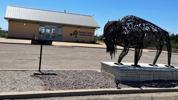Un edificio con la leyenda 'Waconda Visitor & Education Center' y una escultura de metal de un búfalo en su fachada.