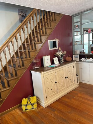 A staircase with wooden balusters, a white cabinet with drawers, and a small table with decorative items. - Waconda Roost (Glen Elder)