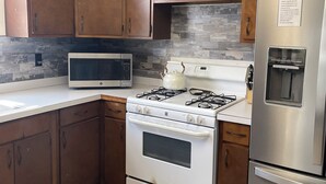 Una cocina con armarios de madera, estufa, microondas y refrigerador.