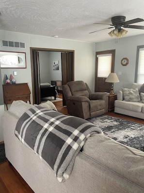 A living room with a sofa, armchair, and a ceiling fan.
