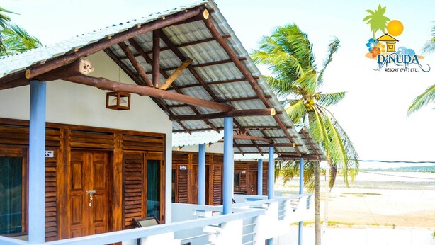 A resort building with wooden doors and a corrugated metal roof, surrounded by palm trees.
