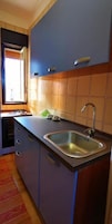 Una cocina compacta con un lavamanos, armarios y una ventana.