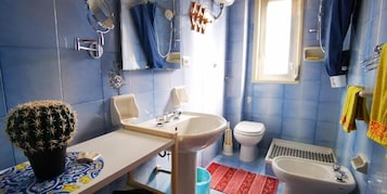 Un baño con lavamanos, inodoro y zona de ducha.