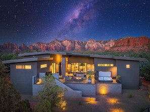 Une maison moderne dotée d’un patio, d’une grande fenêtre et offrant une vue sur les montagnes.