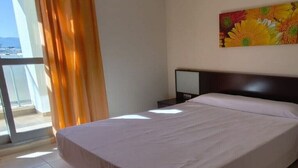 Una camera d'albergo con un letto, una televisione e una finestra con tende.