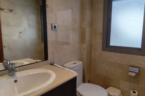 Ein kleines Badezimmer mit Waschbecken, Toilette und Spiegel.