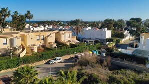 Una zona residenziale sulla costa, con case, palme e un cielo azzurro limpido.