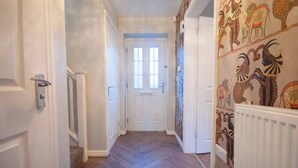 A hallway with a white door at the end, flanked by walls with patterned wallpaper. - Luxe 3BR - 8 Min to Town Centre - Bradgate Park & Leicester - Parking - Garden (Loughborough)
