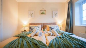 A neatly made bed with green blankets, two bedside lamps, and framed botanical prints on the wall. - Luxe 3BR - 8 Min to Town Centre - Bradgate Park & Leicester - Parking - Garden (Loughborough)