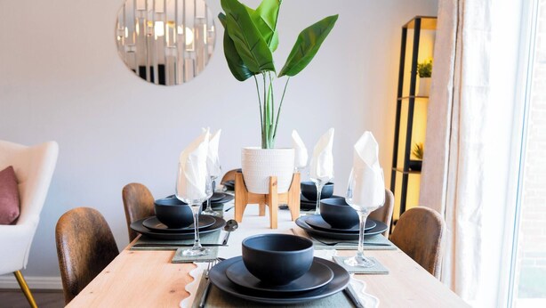 A dining table set with black bowls, plates, and glasses, surrounded by brown chairs. - Luxe 3BR - 8 Min to Town Centre - Bradgate Park & Leicester - Parking - Garden (Loughborough)