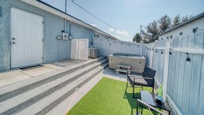 Ein Garten mit Whirlpool, Sitzgelegenheiten im Freien und einer überdachten Terrasse.