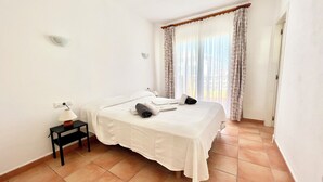A hotel room with a bed, a nightstand, a lamp, and a window with curtains. - Son Bepa , (Cales Piques)