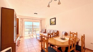 A dining area with a round table, wooden chairs, and a view of the outdoors through a sliding glass door. - Son Bepa , (Cales Piques)