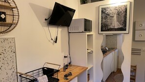 Uma cozinha com micro-ondas, pia, bancada de madeira, cesta preta e um quadro na parede.