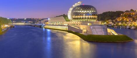 Un edificio moderno con una estructura esférica distintiva y ubicación frente al agua.