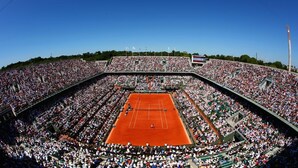 Um grande estádio de tênis coberto, com várias áreas de arquibancada e uma quadra central.