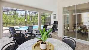 Ein Terrassenbereich mit Pool, Sitzgelegenheiten im Freien und Blick auf die umliegende Bepflanzung.