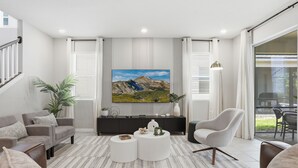 Ein modernes Wohnzimmer mit großem Flachbildfernseher, einer Couch, einem Couchtisch und einem Sessel.