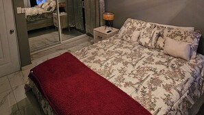 Een slaapkamer met een bed, een plafondventilator, een airconditioning, een spiegel en een nachtkastje.