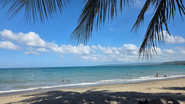 Een strand met heldere luchten en rustig water.