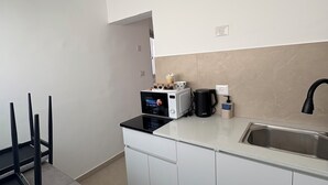 Een moderne keuken met witte kasten, een roestvrijstalen spoelbak, een magnetron en een koffiezetapparaat.
