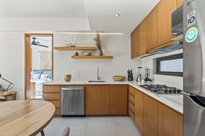 Eine moderne Küche mit Holzausstattung, einem Edelstahl-Geschirrspüler, einem Gasherd und einem Kühlschrank.