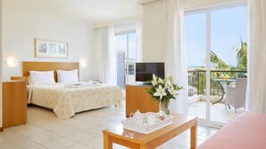 A hotel room with a bed, a TV, a balcony with a table and chairs, and a view of the ocean. - Renaissance Hanioti Resort (Kassandra)