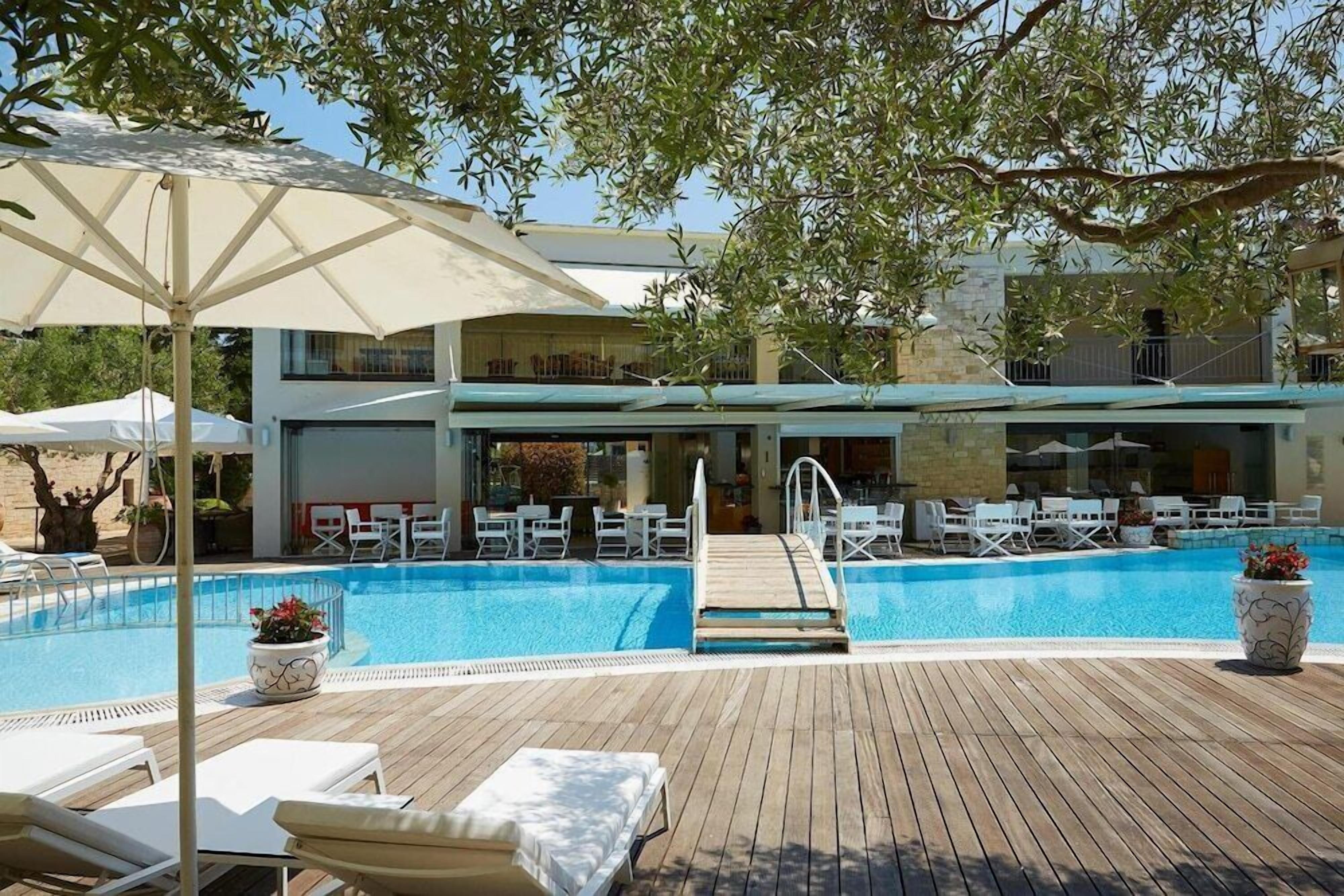 Un espace piscine aménagé avec des chaises longues, des parasols et une terrasse en bois.